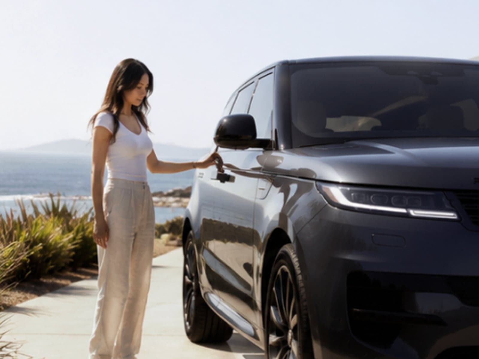 Woman opening her Range Rover after a driveway wash with coastal views